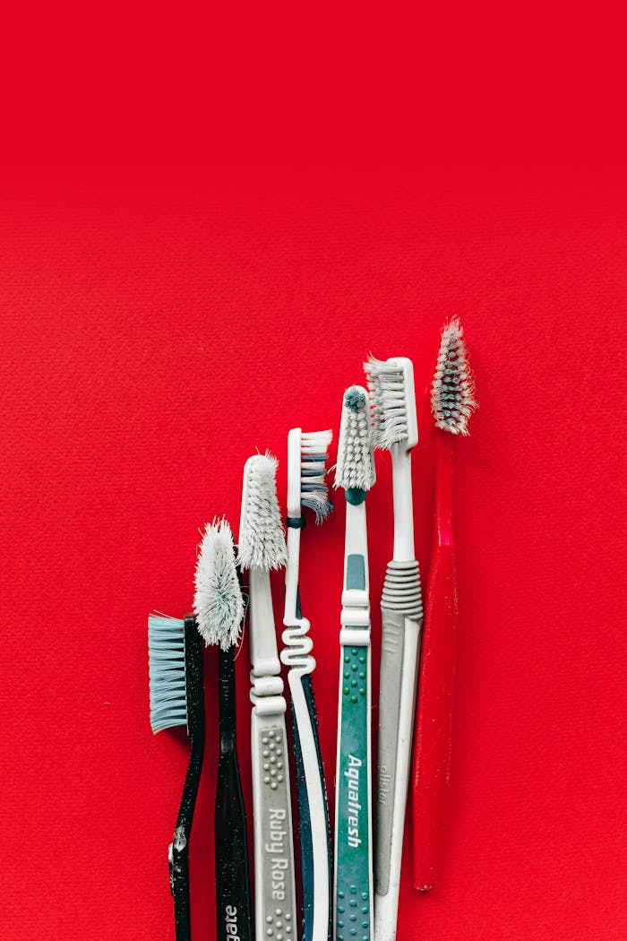 our-services-1 Collection of old and worn toothbrushes on a bright red background, highlighting dental hygiene concepts.